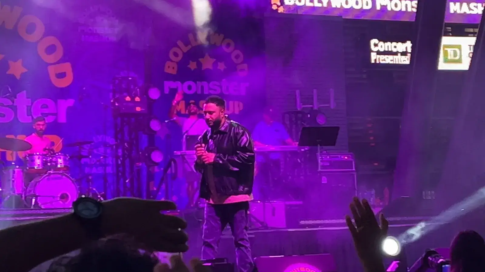 Ash King singing under purple stage lights