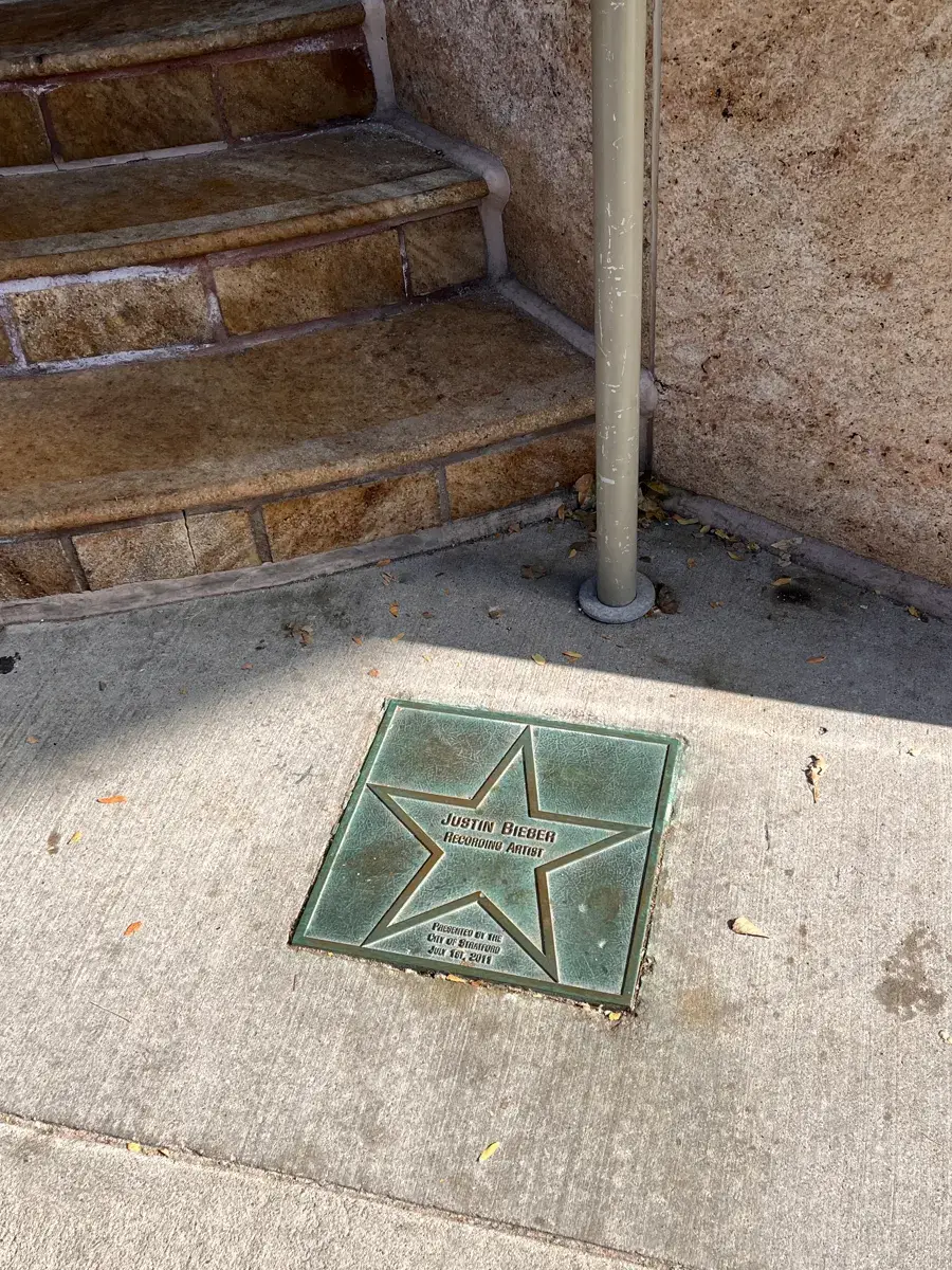 Bronze star plaque in the pavement reading Justin Bieber, Recording Artist, presented by the City of Stratford, July 1st, 2011