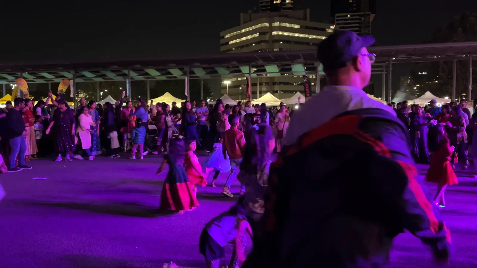 People dancing garba under purple lights