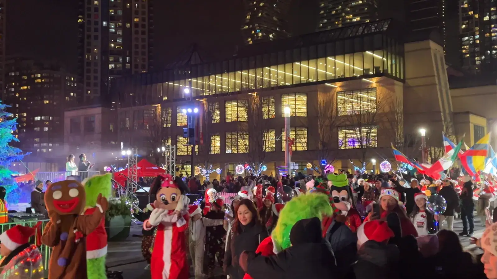 Santa Parade floats and costumed performers passing the Square at night