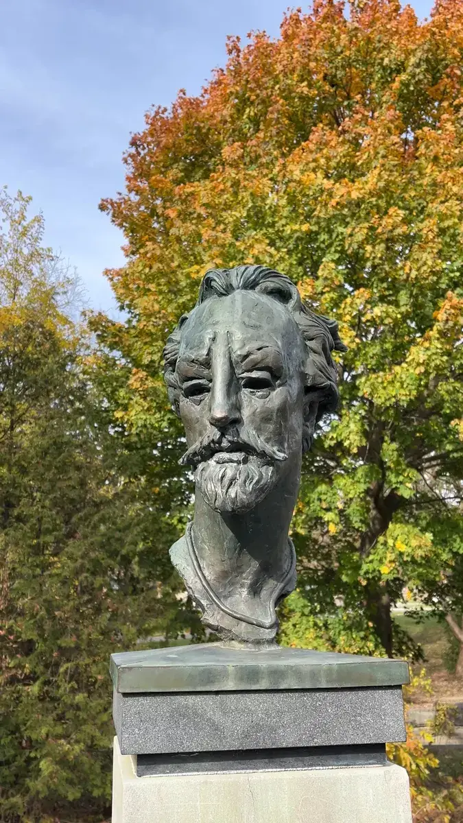 Bronze bust of William Shakespeare in the Shakespearean Gardens, with autumn trees behind